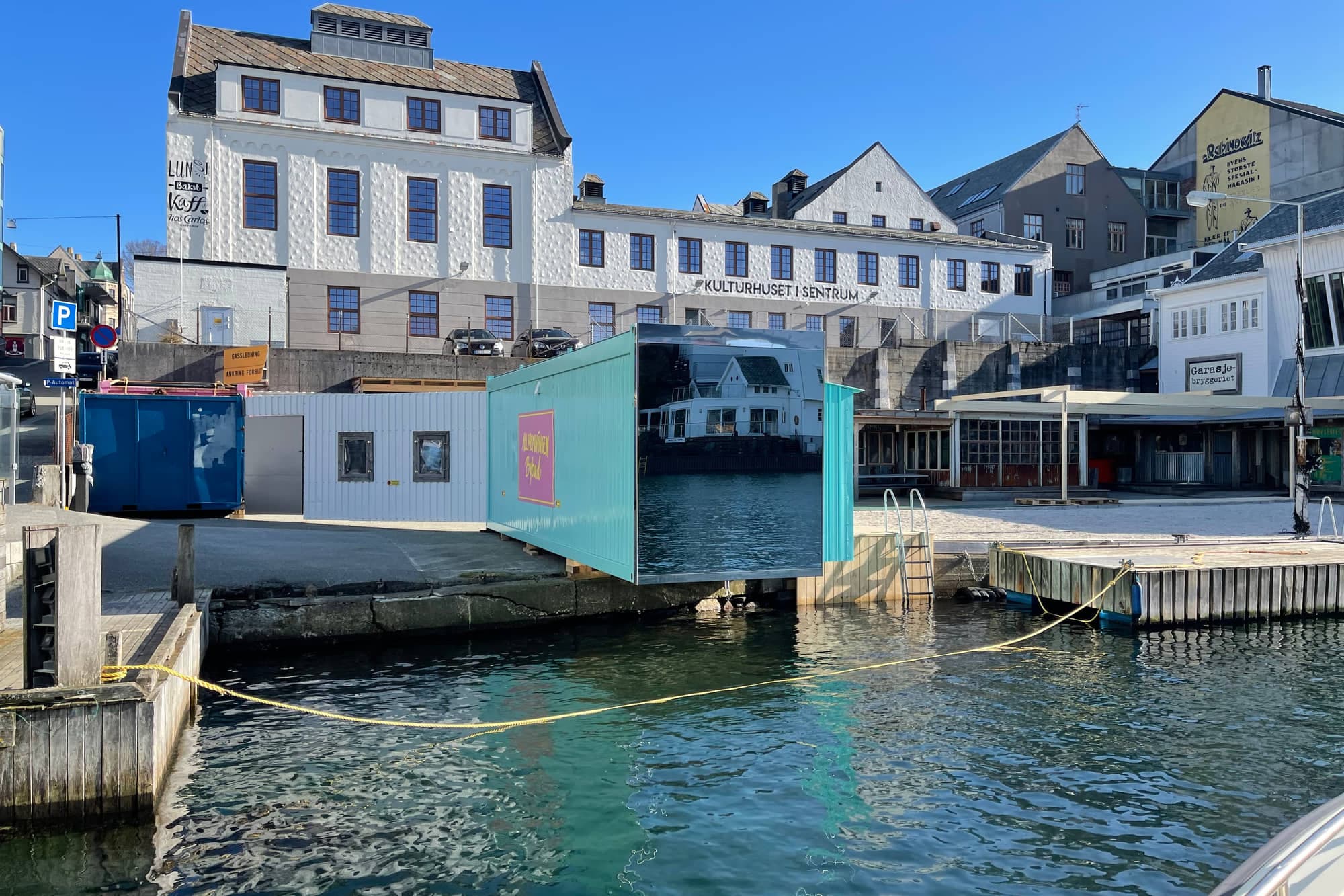 Den mintgrønne containerbadstua på kaikanten ved Høvleriet, med speilvegg mot havnebassenget og badestige rett ned i sjøen.