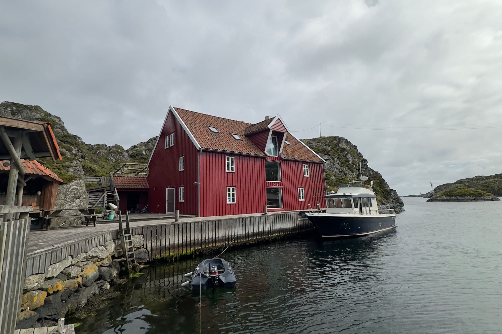 Vindkjeften sett fra brygga i overskyet vær, med båt fortøyd langs kaikanten og sjøen åpen mot høyre.